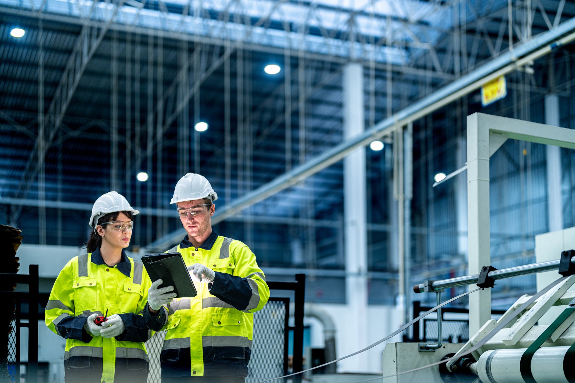 Male and female engineers in neat work clothes prepare and control the production system of large modern machines in a factory producing industrial technology products. Male and female engineers in neat work clothes prepare and control the production system of large modern machines in a factory producing industrial technology products.